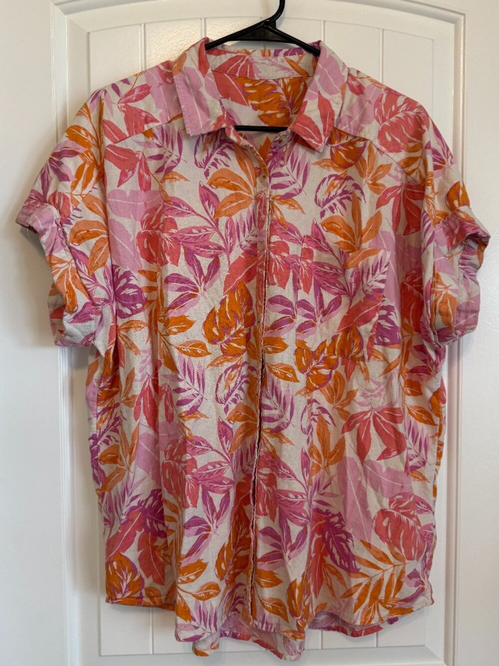 Short-sleeve button-down shirt with vibrant pink and orange tropical leaf print.